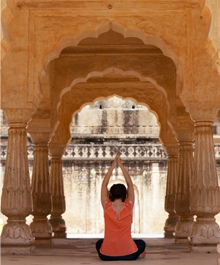 India, Rajasthan, Amber Fort, woman performing yoga Amber Fort woman performing yoga, rear view - Doctor Mosaraf Ali